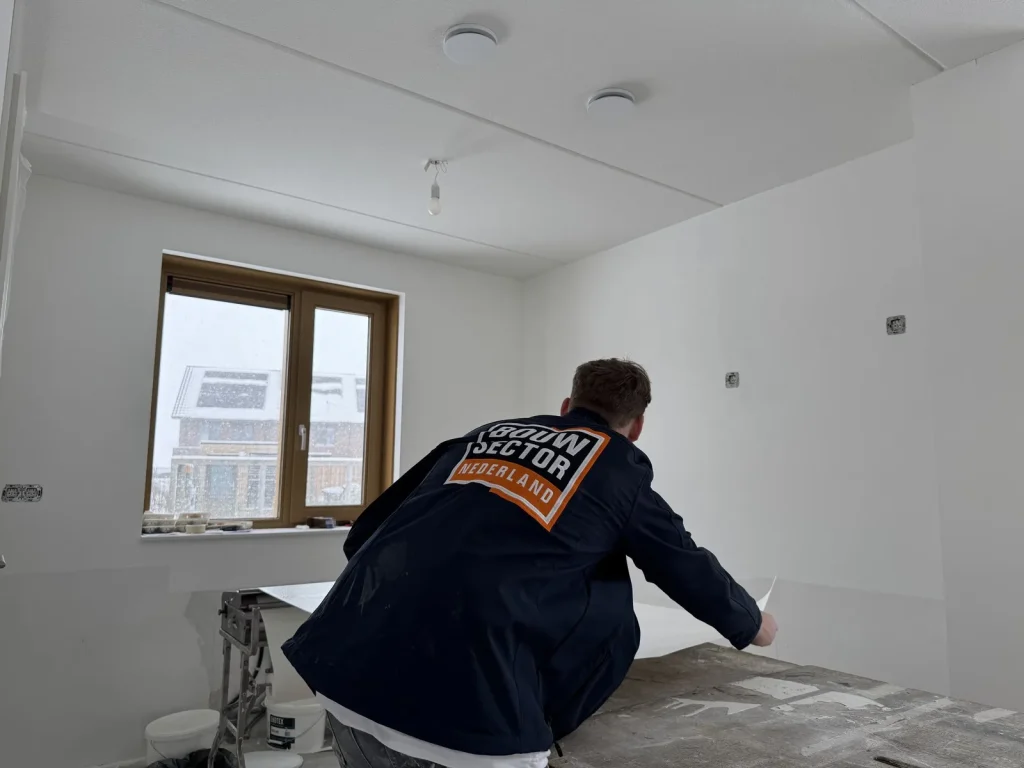 Behanger van Bouwsector Nederland pakt een baan behang van de plaktafel